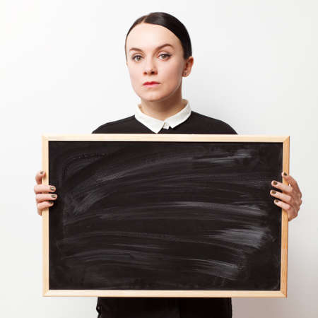 Retro portrait of a strict young woman holding a blackboardの写真素材
