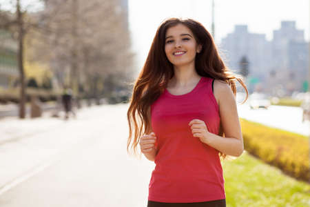 Young beautiful woman running in the city.の写真素材