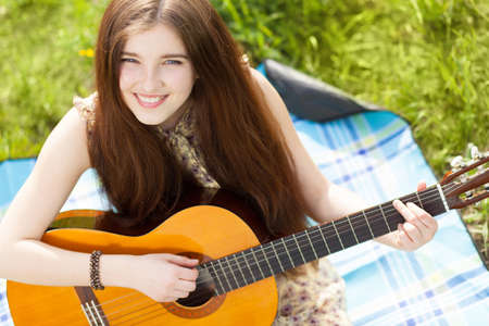Young woman playing an acoustic guitar outdoorsの写真素材