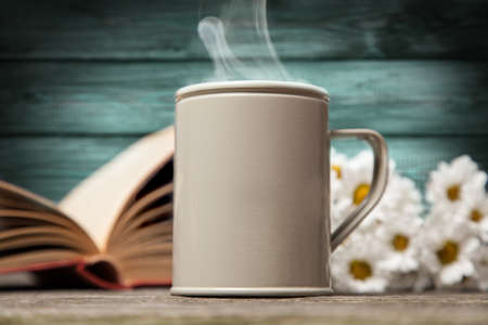 Coffee, daisies and a book on a wooden backgroundの写真素材