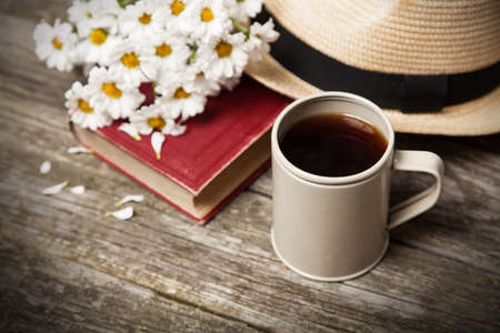 Coffee, daisies and a book on a wooden backgroundの写真素材