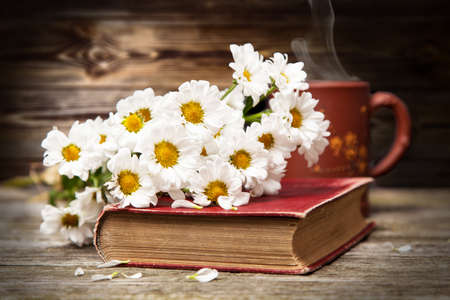 Coffee, daisies and a book on a wooden backgroundの写真素材