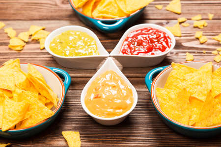 Plate of nachos with salsa, cheese and guacamole dips