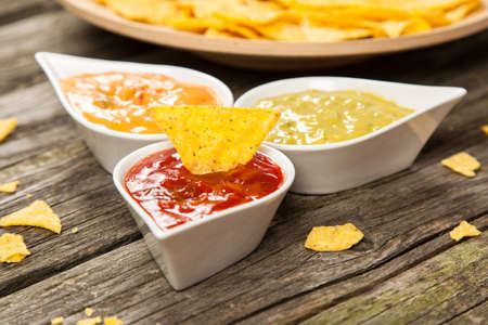 Plate of nachos with salsa, cheese and guacamole dipsの写真素材