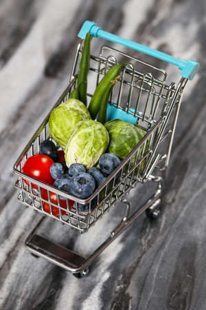 Shopping cart with vegetables on black backgroundの写真素材
