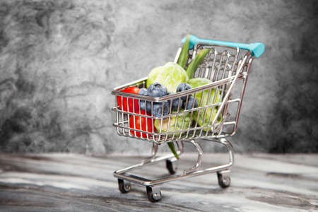 Shopping cart with vegetables on black background.の写真素材
