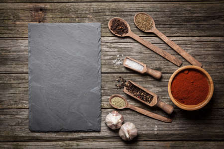 Stone board with different spices on wooden surfaceの写真素材