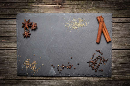 Stone board with different spices on wooden surfaceの写真素材