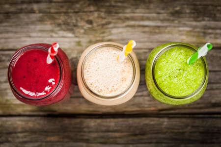 Three milkshakes and smoothies on wooden tableの写真素材