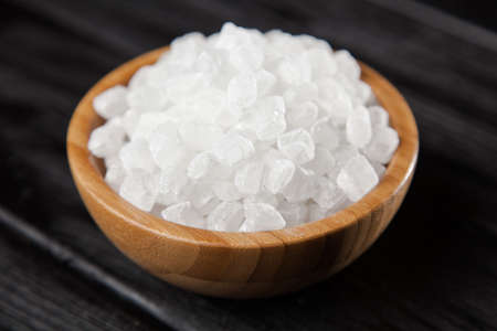 Sugar in a bamboo bowl on black backound