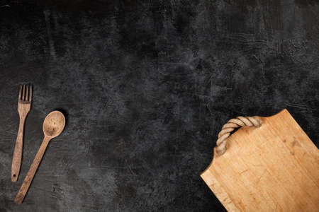 Old wooden cutting board on black background