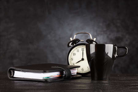Alarm clock and a cup of coffee on dark backgroundの写真素材