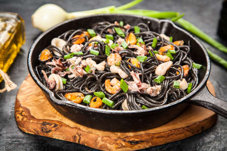 Black spaghetti made of squid ink with shrimps and other seafoodの写真素材