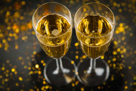 Two Champagne glasses in golden glitter, dark backgroundの写真素材
