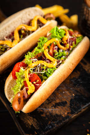Three delicious hotdogs on dark wood backgroundの写真素材