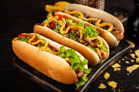 Three delicious hotdogs on dark wood backgroundの写真素材