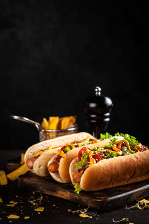 Three delicious hotdogs on dark wood backgroundの写真素材