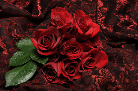 Red roses on textured red and black floral fabricの写真素材
