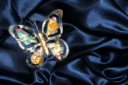 Metal colorful butterfly on blue satin fabricの写真素材