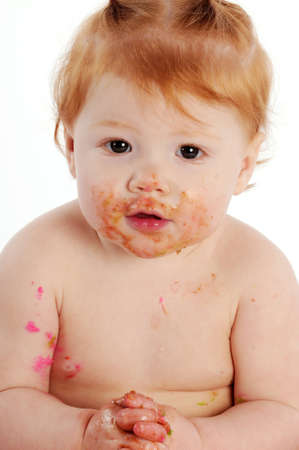 Messy baby with icing on hands and face smilingの写真素材