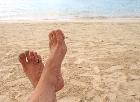 feet of a man relaxing on the beachの写真素材