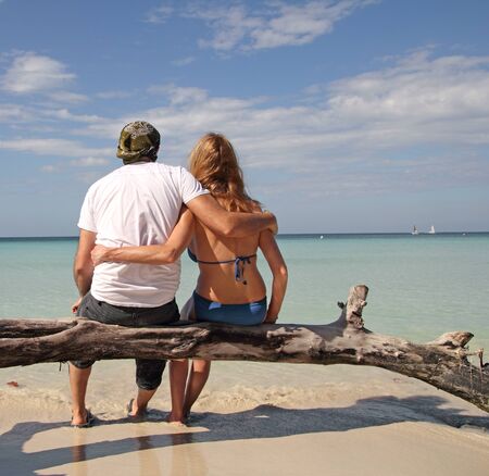 couple sitting on a tree watching at the oceanの写真素材