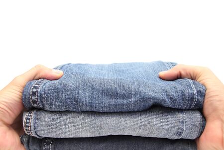 closeup of two hands holding a pile of blue jeansの写真素材
