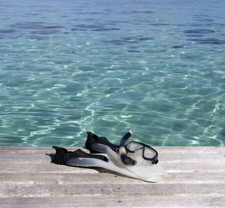 snorkeling equipment on a wood pier over a turquoise lagoonの写真素材