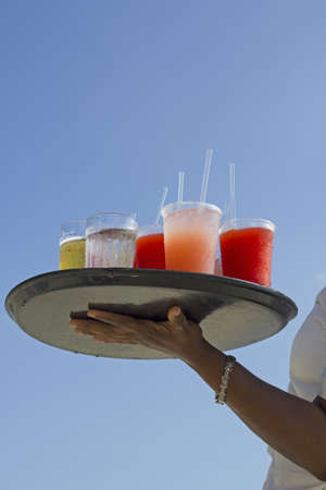black woman arm holding a drinks plate over blue skyの写真素材