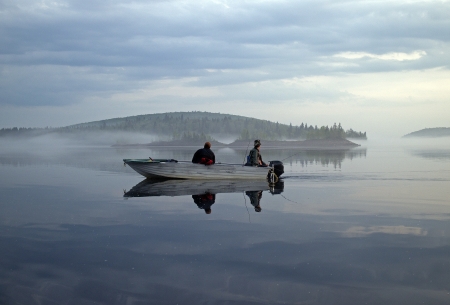  two men in a boat fishing on a calm lakeの写真素材