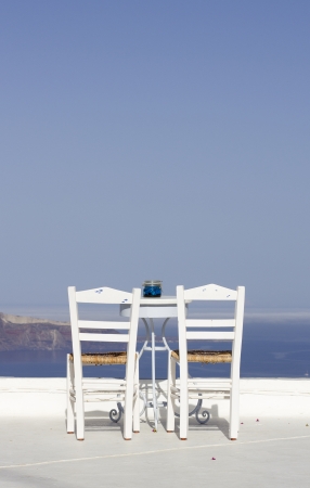 two chairs and a little table facing the sea on a terraceの写真素材