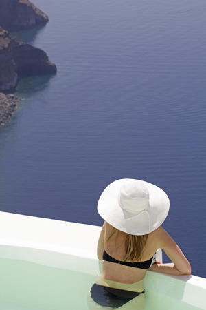 woman watchin the ocean in a private pool on santorini island greeceの写真素材