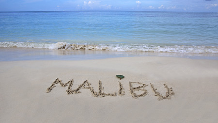 The word Malibu written on the sand by the oceanの写真素材