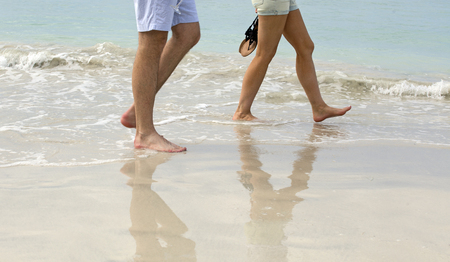 Walking on the beach with reflection on the wet sandの写真素材