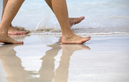 Walking on the beach with reflection on the wet sandの写真素材