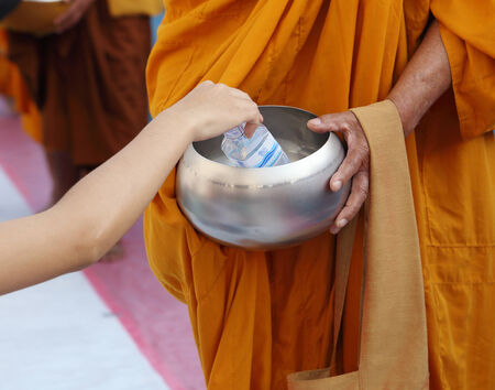 NAKHON RATCHASIMA, THAILAND - FEB 8:Hand while put food offerings in a Buddhist monk's alms bowl in the occasion celebrating 357-year anniversary of Nakhon Ratchasima city at Chumphon Rd. in Nakhon Ratchasima, Thailandのeditorial素材