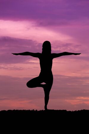 Silhouette of a beautiful Yoga woman at sunsetの写真素材