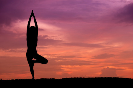 Silhouette of a beautiful Yoga woman at sunsetの写真素材