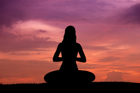 Silhouette of a beautiful Yoga woman at sunsetの写真素材