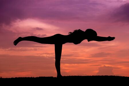 Silhouette of a beautiful Yoga woman at sunsetの写真素材