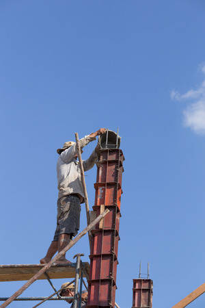 NAKHON RATCHASIMA -DEC 28 : worker pouring cement to concrete pillar mold for house construction on December 28, 2015 in Nakhon Ratchasima, Thailandのeditorial素材