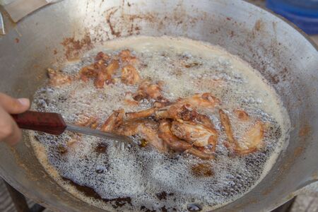 chicken deep frying in oil in a pan at marketの写真素材