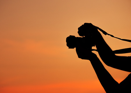 Silhouette of hand shooting with a camera at sunsetの写真素材