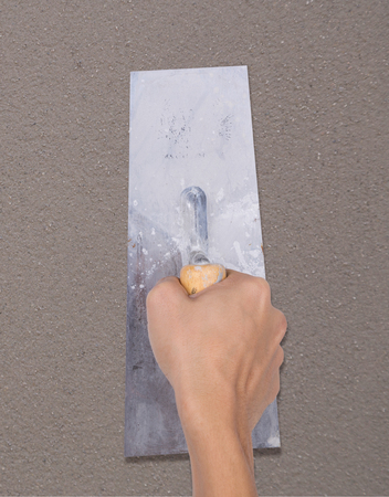 hand of builder worker use trowel plastering concrete at wallの写真素材