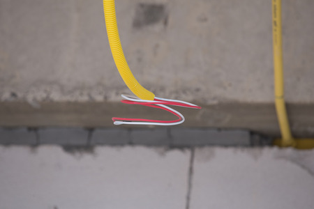 yellow PVC pipes for electrical boxes and wires buried on concrete wall at construction site