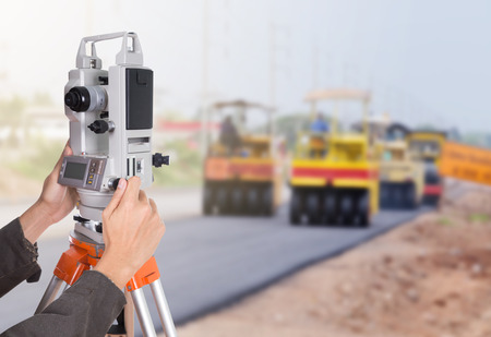 hand working with survey equipment theodolite on a tripod. with road under construction backgroundの写真素材