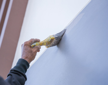 Hand holding brush painting wall with gray colorlの写真素材