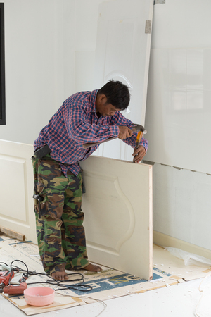 NAKHON RATCHASIMA -JUNE 21 : carpenter installer works with hammer and chisel at wood door on June 21, 2016 in Nakhon Ratchasima, Thailandの写真素材
