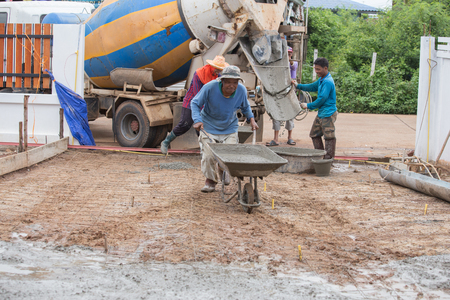 NAKHON RATCHASIMA -JULY 6 : Construction worker pushing barrow with wet cement to pouring concrete floor on July 6, 2016 in Nakhon Ratchasima, Thailandのeditorial素材