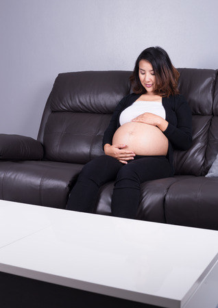 portrait of pregnant woman resting at home on sofaの写真素材